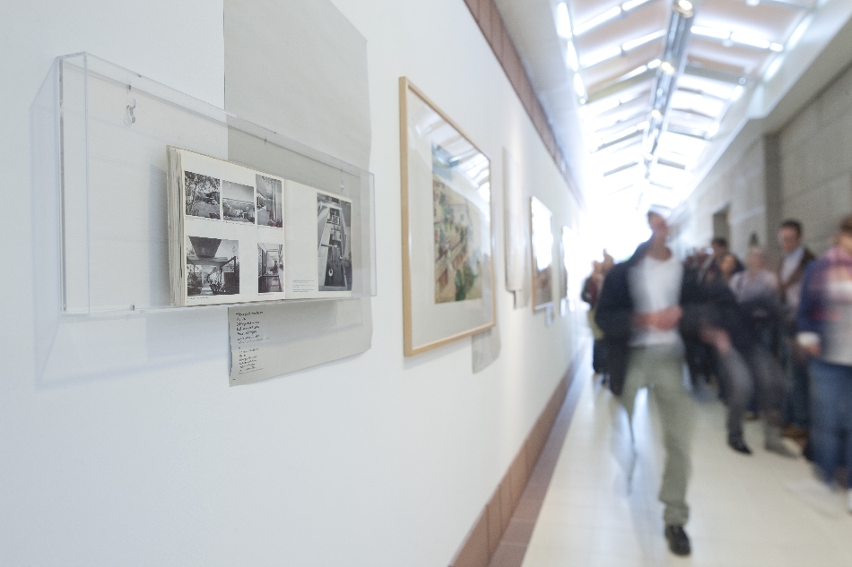 Bild vergrössern: Gruppe von Menschen (verschwommen, rechts) im Gang des Architekturmuseums, links Fotos an der Wand