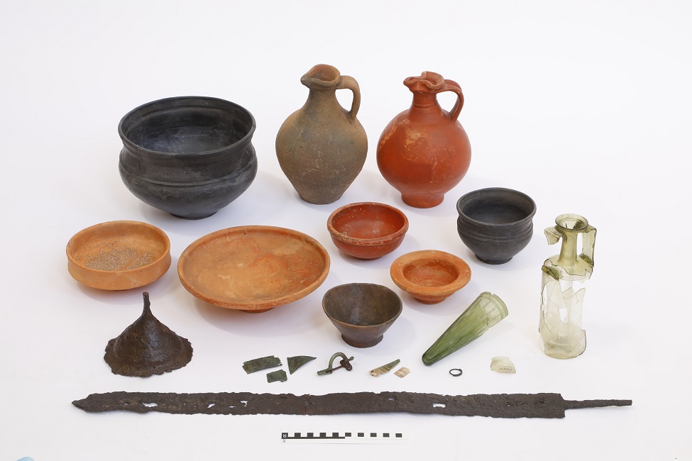 Mehrere Schalen und Amphoren in unterschiedlichen Größen und Farben und eine verrostete Schwertklinge