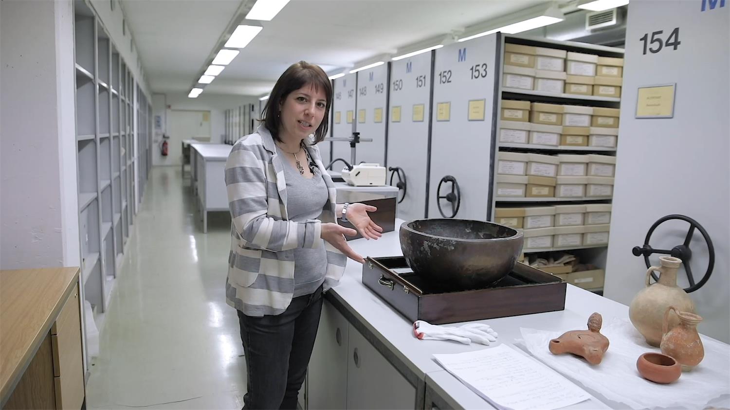 Die Kuratorin Dr. Natascha Bagherpour steht vor einer Theke mit einer großen Schale im Lager des Archäologischen Museums