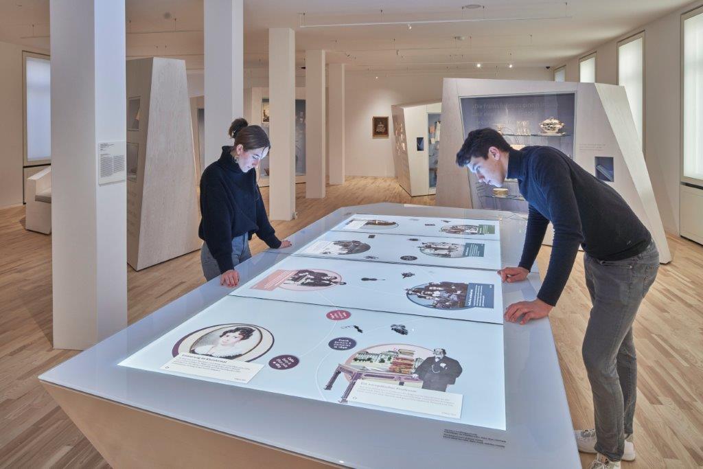 Bild vergrössern: Zwei Menschen beugen sich über einen Medientisch im Jüdischen Museum Frankfurt