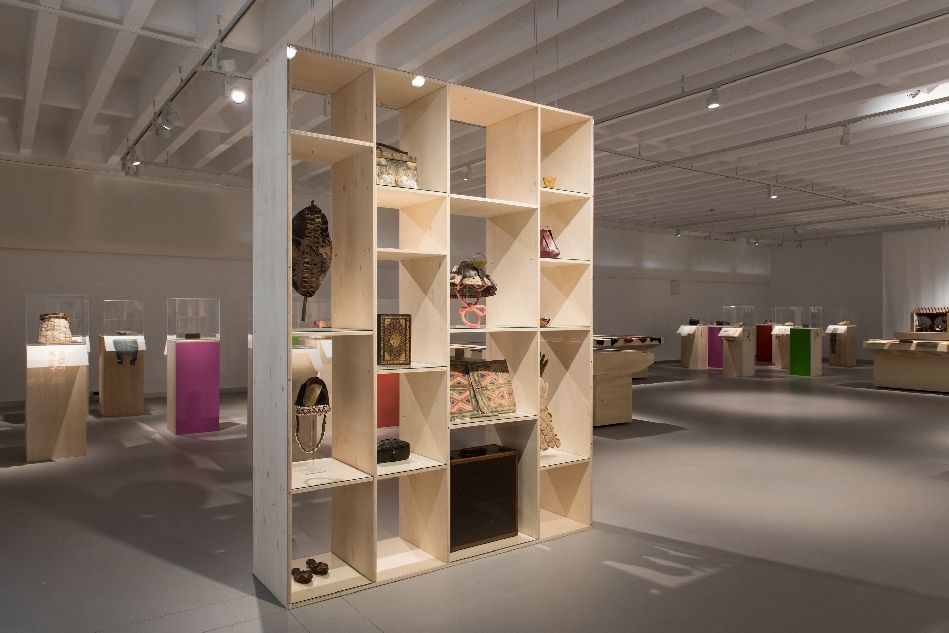 Ausstellungsansicht "Das ist Leder!" im Ledermuseum mit Regal mit Objekten im Vordergrund und Fühlstationen im Hintergrund