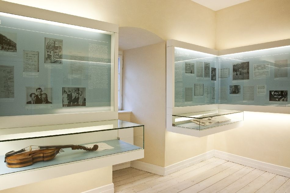 Ausstellungsansicht im Hindemith Kabinett mit in die Wand eingelassenen Vitrinen und einer liegenden Geige vorne links
