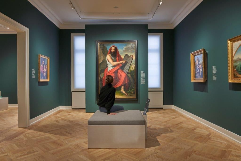 Eine junge Frau sitzt vor einem Gemälde in der Dauerausstellung des Jüdischen Museums Frankfurt