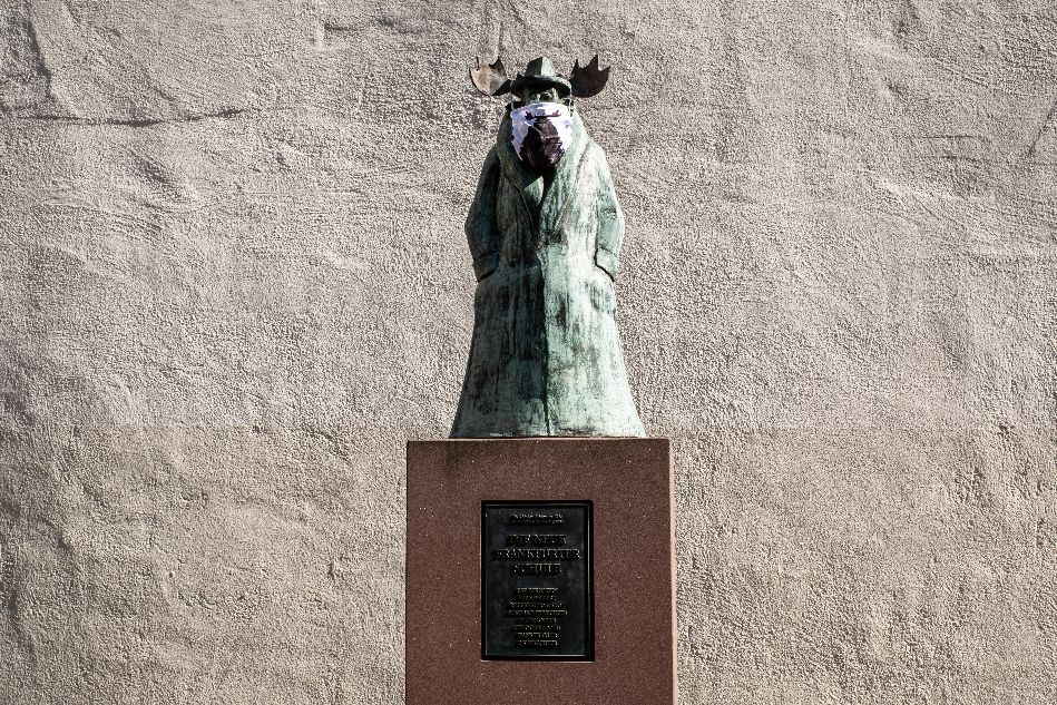 Statue von einem stehenden Elch im Mantel mit Maske vor dem Caricatura Museum