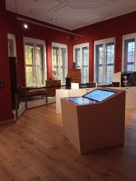 Ausstellung im Stoltze-Museum mit Medientisch mittig und Möbelpodest im Hintergrund