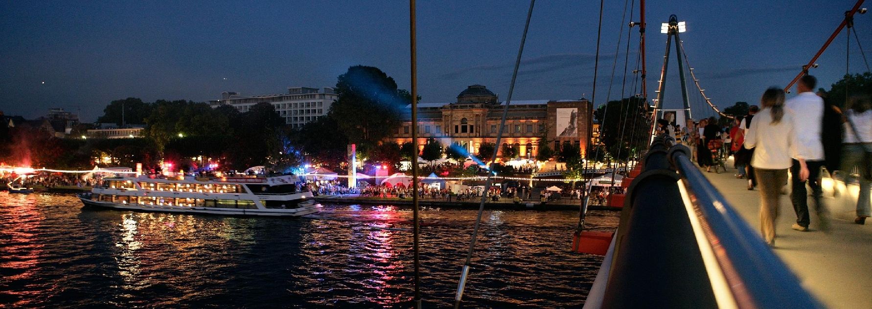 Mainufer von der Städelbrücke mit Fassade des Städel Museums, Schiff und Menschen im Hintergrund bei Nacht