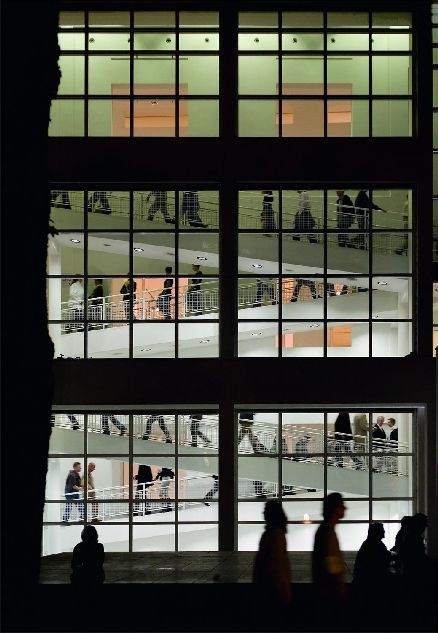 Ausschnitt der Fassade des Museums Angewandte Kunst, durch deren Fenster man die Silouetten der Besucher*innen im Aufgang sieht 