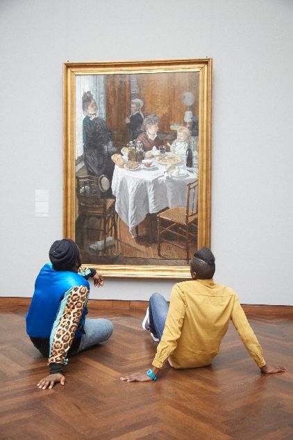Zwei Besucher sitzen vor einem Gemälde von Claude Monet ("Das Mittagessen") im Städel Museum