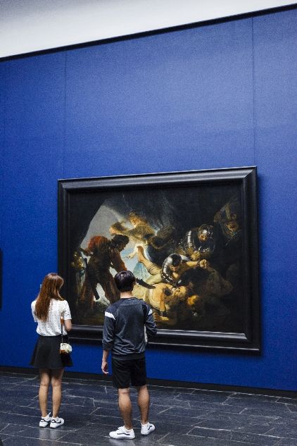 Ein Pärchen betrachtet ein Gemälde im Städel Museum vor blauer Wand
