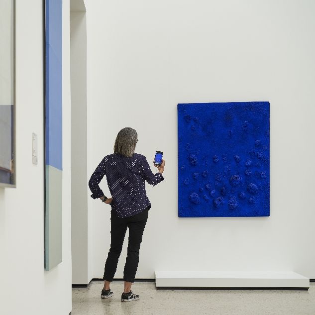 Frau mit Handy steht vor blauem Bild von Yves Klein im Städel Museum