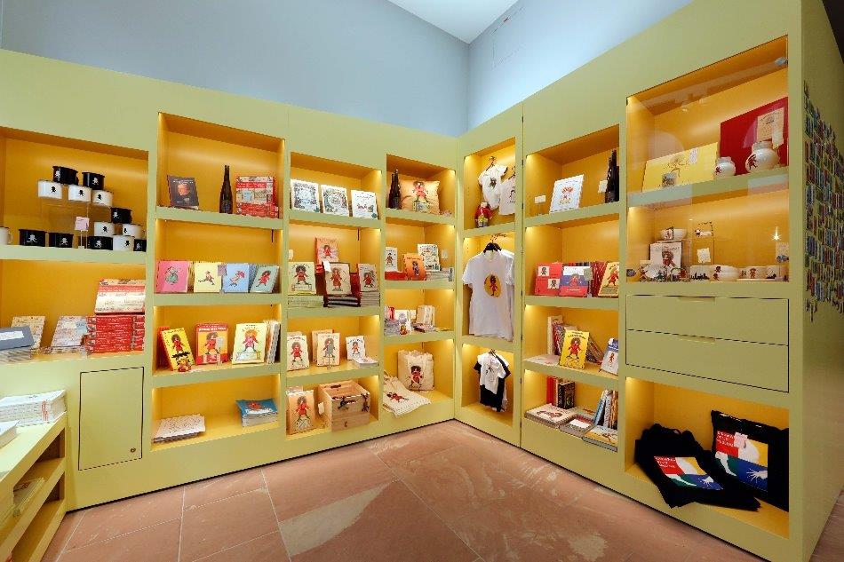 Ecke des Shops im Struwwelpeter Museum mit gelben Regalen mit Büchern, T-Shirts, Tassen und vielem mehr rund um den Struwwelpeter