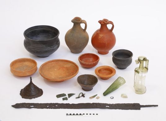 Mehrere Schalen und Amphoren in unterschiedlichen Größen und Farben und eine verrostete Schwertklinge