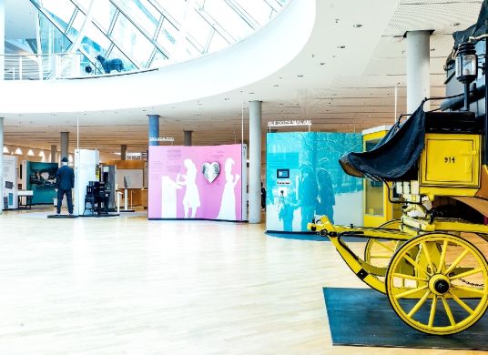 Großer Ausstellungsraum mit angeschnittener Postkutsche im Vordergrund rechts