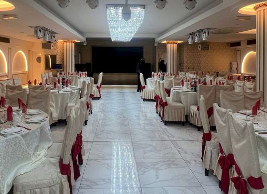 Dieses Bild zeigt einen eleganten, hell erleuchteten Bankettsaal oder ein gehobenes Restaurant, das sorgf&auml;ltig f&uuml;r eine gro&szlig;e Veranstaltung vorbereitet wurde.