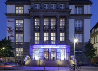 DFF – Deutsches Filminstitut & Filmmuseum, Fassade bei Nacht mit beleuchtetem Eingang, Straße im Vordergrund