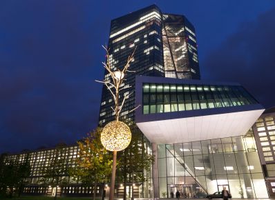 Eingang zur Europäischen Zentralbank mit kleinem Baum mit Lichtkugel im Vordergrund, dahinter verglastes Hochhaus 