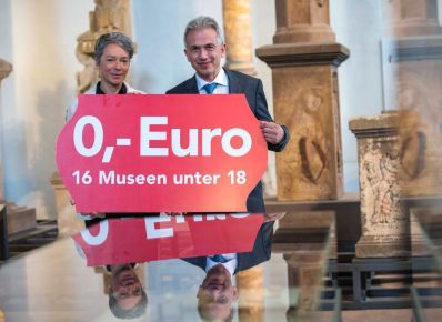 Die Kulturdezernentin und der Oberbürgermeister halten ein Plakat in der Hand, darauf der Text: Null Euro, 16 Museen unter 18 Jahre