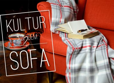 Sofa mit Decke und aufgeschlagenem Buch und dem Schriftzug "Kultur auf dem Sofa"