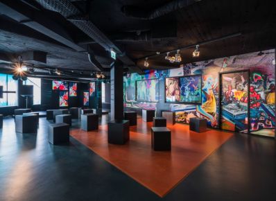 Ausstellung im MOMEM – Museum of Modern Electronic Music mit bunten Medienwänden im Hintergrund bei und schwarzen Sitzwürfeln im Vordergrund
