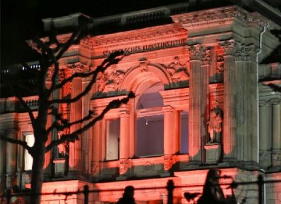 Eingang des Städel Museum in rötlichem Licht angestrahlt mit Fahrrädern im Vordergrund