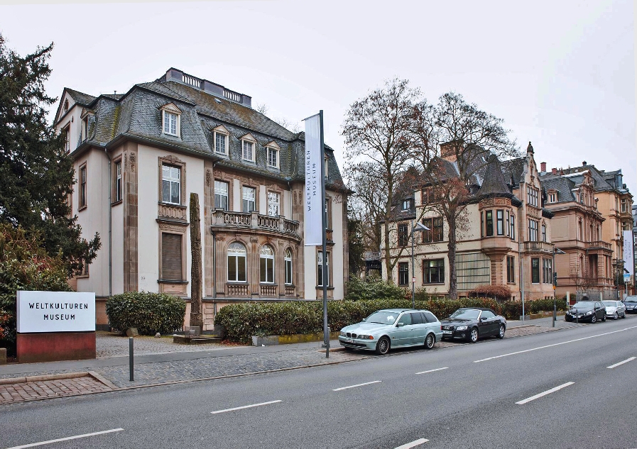 Enlarge image: Die Gebäude (Altbau-Villen) des Weltkulturen Museums von der gegenüberliegenden Straßenseite fotografiert und parkenden Autos davor