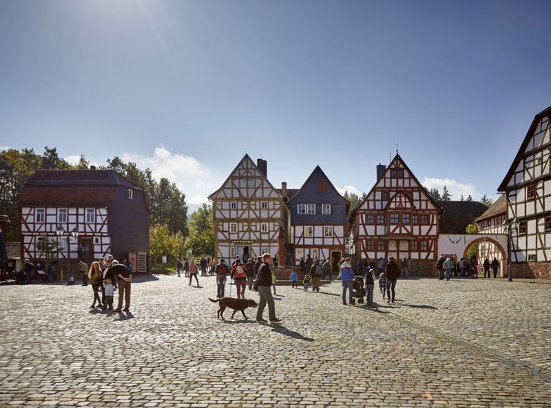 Freilichtmuseum Hessenpark © Jens Gerber Ein Platz mit mehreren Fachwerkhäusern und Menschen bei Sonnenschein