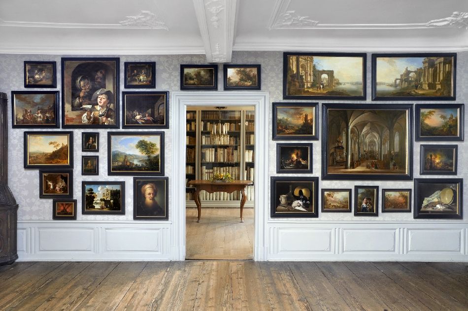 Wand mit vielen Gemälden an der Wand im Goethe-Museum und Blick durch die Tür zur Bibliothek